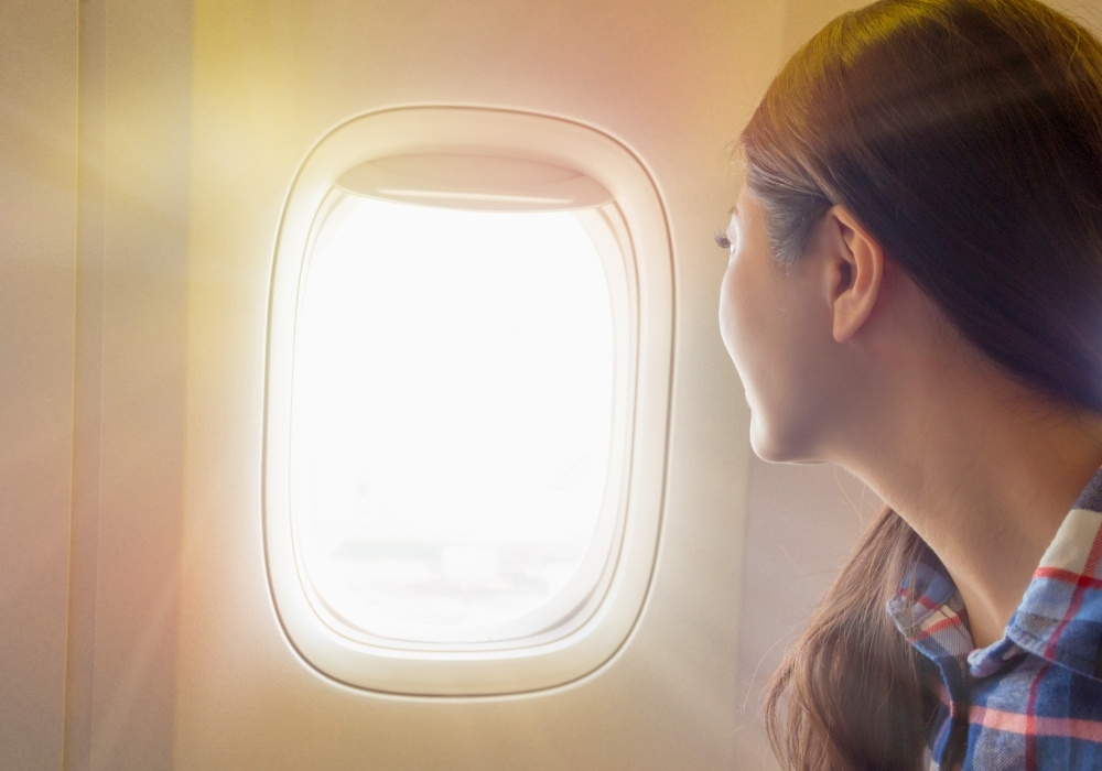 飛行機の窓から外を見る女性