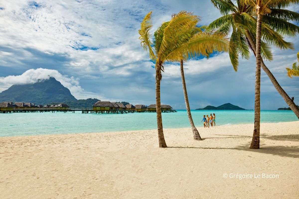 タヒチのラグーンで家族がビーチを歩く様子